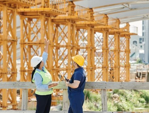 a man and a woman with ppe s talking at a construction site